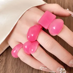 Detailed view of pink geometric resin rings with marble texture worn on model hand
