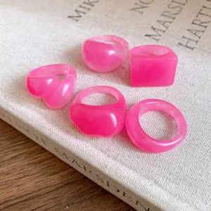 Macro view of five pink resin rings with marbled texture and various geometric shapes