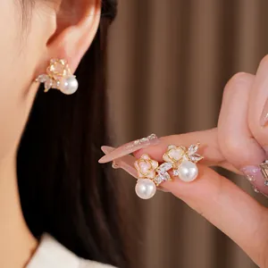 Detalle de pendientes de flor y perla con circonitas brillantes