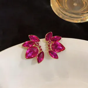 Primo piano di eleganti orecchini a petalo magenta con bordo dorato e brillanti strass