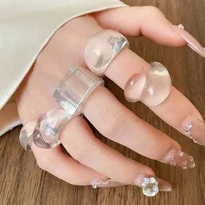Close-up of transparent resin rings with geometric shapes on hand