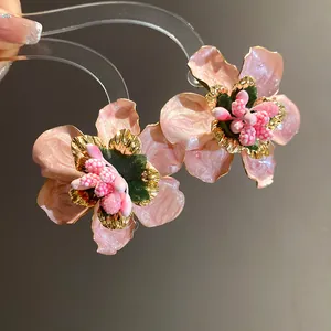 Primo piano di orecchini a perno a fiore in smalto rosa con dettagli dorati bohémien.