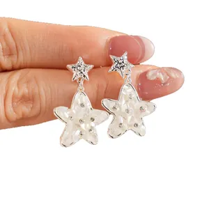 Eleganti orecchini pendenti a stella in argento con intarsio in conchiglia e strass.