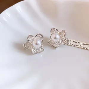 Macro detail of elegant French vintage hollow flower earrings featuring pearls and zircons