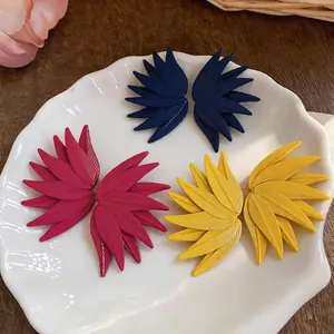 Close-up of three pairs of leaf-textured stud earrings in navy, fuchsia, and mustard yellow.