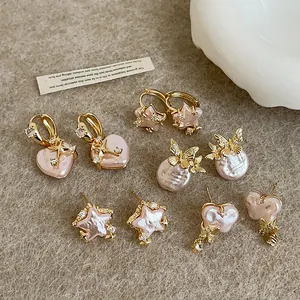 Close-up macro detail of elegant pink pearl earrings with gold star and heart accents.