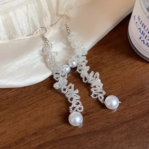 Detail shot of elegant handmade beaded long dangle earrings with white faux pearls