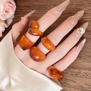 Detailed view of amber resin rings with marbled texture on a model's hand