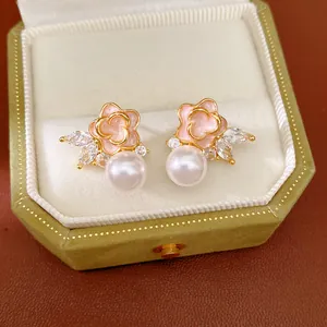 Primer plano de pendientes de flores esmaltadas rosas con perlas blancas y circonitas.