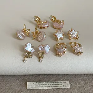 Detailed view of pink pearl earrings with butterfly and star motifs in gold finish