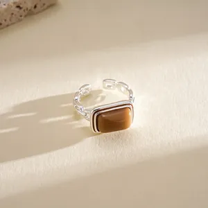 Close-up of a silver geometric open ring featuring a rectangular brown resin stone.