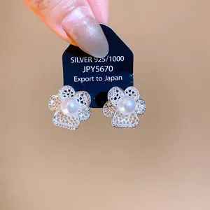 Detailed close-up of retro hollow flower stud earrings with a central white pearl