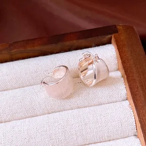 Close-up of minimalist 18k gold plated hoop earrings with brushed metal texture