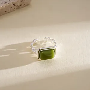 Close-up of a geometric silver ring featuring a square olive green resin center stone