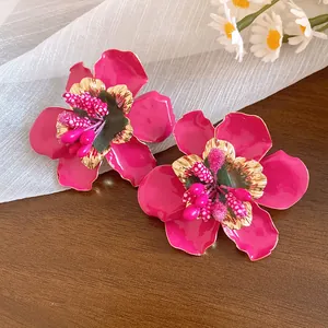 Primo piano di orecchini a fiore in smalto magenta con centro dorato testurizzato