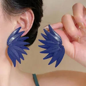 Detailed view of navy blue leaf-textured wing stud earrings shown on model's ear