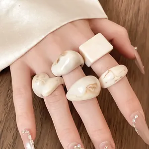 Detailed view of cream resin rings with brown marble patterns on model's hand