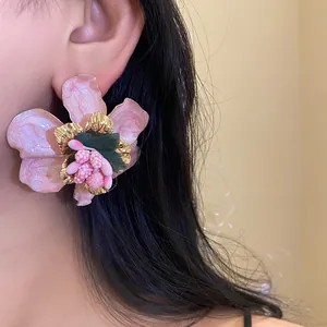 Primo piano di orecchini a perno a forma di fiore rosa in stile bohémien vacanza