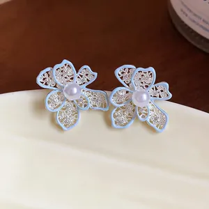 Orecchini a fiore in smalto celeste con perla centrale e petali traforati in dettaglio.
