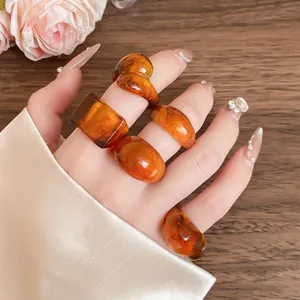 Detailed close-up view of multiple amber-colored marbled resin rings on a hand