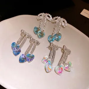 Elegant iridescent bow earrings with heart-shaped crystals on a cream plate
