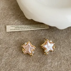 Close-up of elegant gold star earrings featuring pink mother-of-pearl and zircons