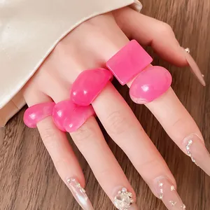 Detailed close-up of pink resin marbled rings in various shapes worn on a hand