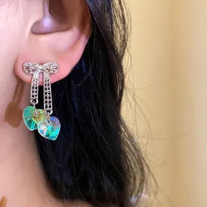 Elegant silver bow earrings featuring iridescent heart crystals with holographic shine