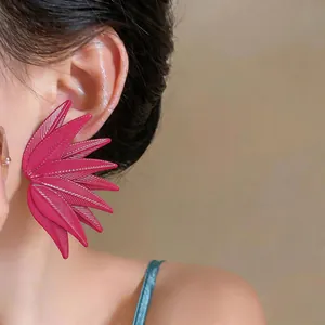 Detailed view of bold magenta leaf-textured statement earrings worn on a model's ear.