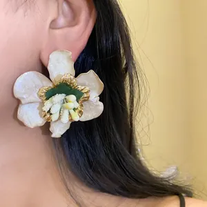 Vista macro dettagliata di orecchini a lobo a fiore bianco perlato con eleganti accenti d'oro