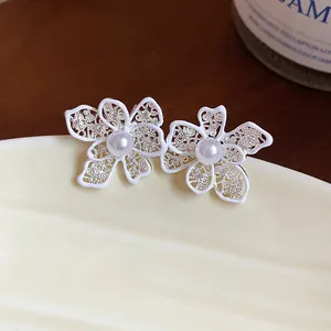 Dettaglio degli orecchini a lobo a fiore traforato bianco con perle su un piatto di ceramica