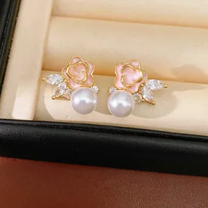 Primer plano de pendientes de flor de esmalte rosa con perlas y circonitas brillantes
