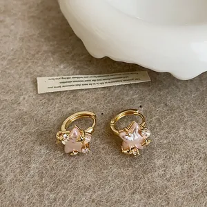 Close-up view of elegant gold hoop earrings featuring pink shell stars and cubic zirconia