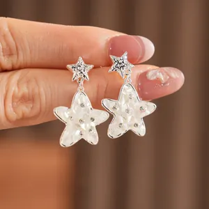 Primo piano dettagliato di orecchini a stella d'argento con intarsio in conchiglia e strass