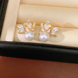 Detalle de pendientes de flores y perlas con esmalte rosa brillante e incrustaciones de circón