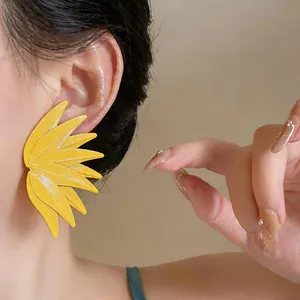 Close-up view of vibrant yellow leaf-patterned statement stud earrings for women