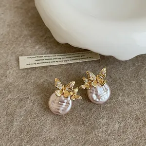 Close-up detail of elegant golden butterfly earrings with pink pearls and zircon accents