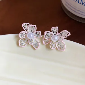 Dettaglio di orecchini a fiore rosa traforati con perla e piccoli strass
