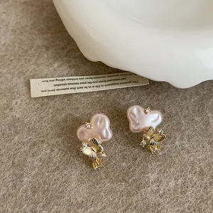 Detail shot of pink heart pearl earrings with gold butterfly and zircon charms
