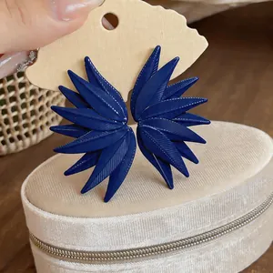 Detailed view of dark blue leaf-textured stud earrings resting on a velvet jewelry box