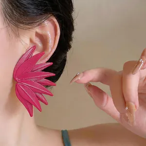 Macro view of a vibrant magenta leaf-textured exaggerated earring on a model's ear.