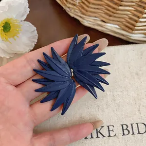 Detailed macro view of dark blue leaf-textured stud earrings with artistic design