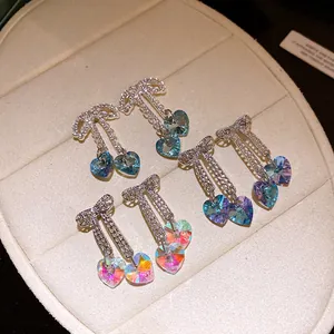 Macro detail of three pairs of iridescent crystal bow tassel earrings on display