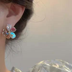 Détail exquis en gros plan d'une boucle d'oreille fleur en verre coloré portée sur l'oreille