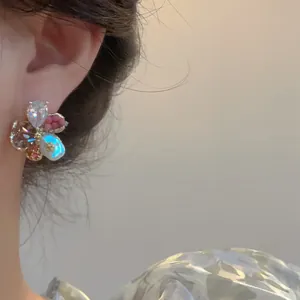 Détail de boucles d'oreilles fleurs en verre coloré de style vintage porté à l'oreille
