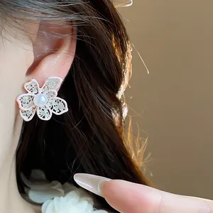 Dettagliato primo piano di un orecchino a fiore rosa traforato con perla sull'orecchio