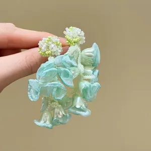 Detailed view of green chiffon flower earrings with delicate beadwork and pearls
