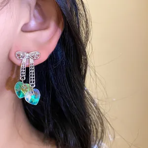 Detail of iridescent heart crystals dangling from a sparkling silver bow earring