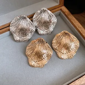 Elegant gold and silver metallic wrinkled leaf shell stud earrings in gray jewelry box