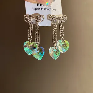 Detailed view of iridescent heart crystal tassel earrings with bow design.
